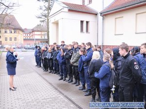 Grupa młodzieży prze budynkiem KMP policjantka w mundurze