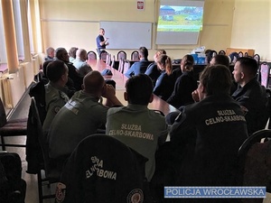 Policjant oraz funkcjonariusze Służby Celno-Skarbowej podczas szkolenia w sali wykładowej