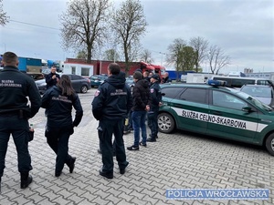 Policjant w trakcie prowadzonego szkolenia, stojący na placu, przed funkcjonariuszami Służby Celno-Skarbowej