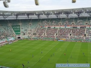 Murawa stadionu w tle trybuny z kibicami na boisku piłkarze