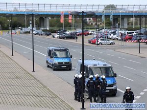 Teren przed stadionem policjanci w mundurach policyjne radiowozy