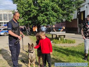 Policjant w mundurze z psem służbowym oraz dwóje dzieci