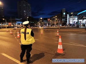 Stojąca na jednej z wrocławskich ulic umundurowana funkcjonariuszka ruchu drogowego kierująca ruchem