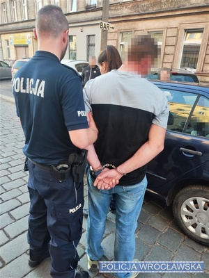 Zatrzymany na jednej z wrocławskich ulic mężczyzna trzymany przed autem przez umundurowanego policjanta