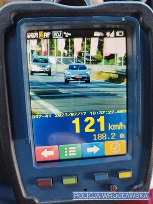 Zdjęcie ekranu laserowego ręcznego miernika prędkości z zarejestrowanym przekroczeniem prędkości 121 km/h przez kierującego oplem.