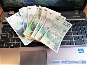 Leżące na otwartym laptopie banknoty o różnym nominale