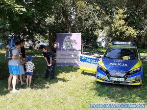 Policjanci w mundurze radiowóz oznakowany oraz grupa dzieci