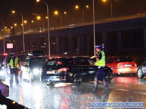 Policjanci w mundurach na jezdni kierują ruchem w kamizelkach odblaksowych