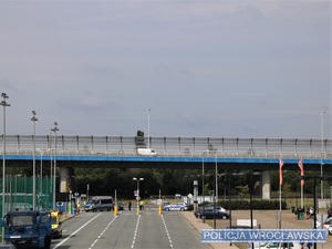 Widok jednej z bram wjazdowych na stadion we Wrocławiu ze stojącymi wzdłuż pojazdami Policji.