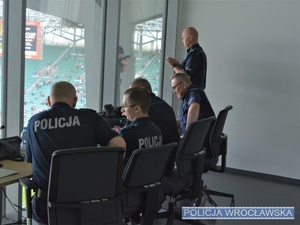 Stojący obok siedzących obok w pomieszczeniu Zastępca Komendanta Miejskiego Policji we Wrocławiu podinsp. Sławomir Wołk prowadzący rozmowę telefoniczną.