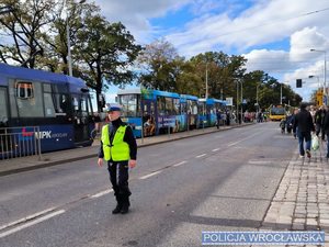 Policjant w mundurze stojący na jezdni kierujący ruchem