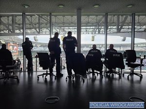 Wnętrze pomieszczenia na stadionie miejskim we Wrocławiu, z którego dowódca zabezpieczania mł. insp. Oktawiusz Cieślik wraz z pozostałymi policjantami obserwuje przebieg meczu.