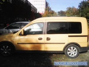 Zdjęcie lewego boku auta marki Opel Combo stojącego na parkingu.