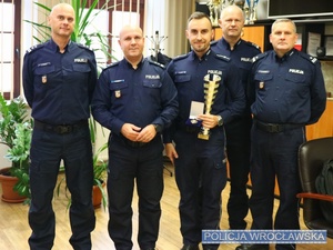 Stojący w gabinecie od lewej Zastępca Komendanta Miejskiego Policji we Wrocławiu mł. insp. Sławomir Wołk, Komendant Miejski Policji we Wrocławiu mł. insp. Rafał Siczek, mł. asp. Paweł Mońka, Komendant Komisariatu Policji Wrocław-Stare Miasto mł. insp. Krzysztof Mossoń oraz Zastępca Komendanta Komisariatu Policji Wrocław-Stare Miasto podinsp. Andrzej Kamiński