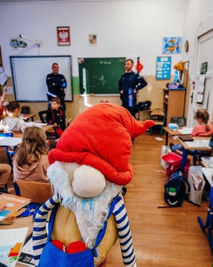 Policjanci podczas prelekcji w szkole i siedzące przed nimi w ławkach dzieci.