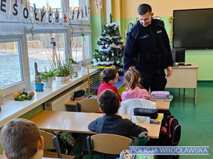Prowadzący w szkolnej klasie pogadankę z dziećmi umundurowany policjant.