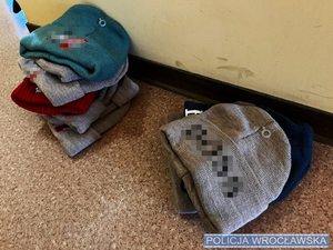 Leżące na korytarzu, na podłodze czapki zimowe z logo znanych światowych marek