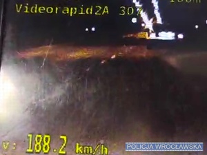 Zrzut z ekranu wideorejestratora z uwiecznionym wykroczeniem przekroczenia prędkości przez kierującego samochodem osobowym.