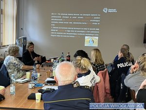 Uczestnicy szkolenia w sali budynku komendy miejskiej policji we Wrocławiu w tle wyświetlana prezentacja