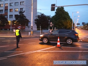 Funkcjonariusz ruchu drogowego nadzorujący ruch na jednym z  wrocławskich skrzyżowań w trakcie zabezpieczenia 10 edycji Nocnego Półmaratonu we Wrocławiu.