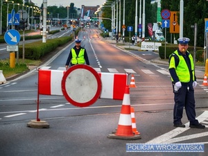 Funkcjonariusze ruchu drogowego nadzorujący ruch na jednym z  wrocławskich skrzyżowań w trakcie zabezpieczenia 10 edycji Nocnego Półmaratonu we Wrocławiu.