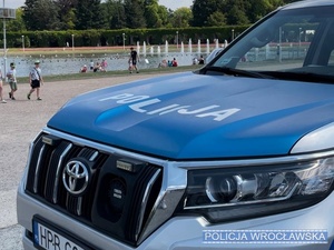 Oznakowany radiowóz Policji stojący przed fontanną przy Hali Stulecia we Wrocławiu.