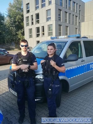 Umundurowani policjanci stojący przy radiowozie