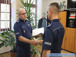 Komendant wręczający nagrodę policjantowi