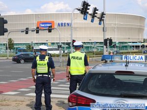 Stojący umundurowani policjanci przy radiowozie