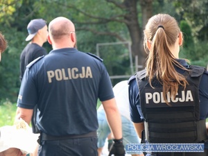 Policjanci pomagający układać worki z piaskiem