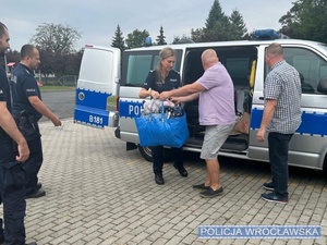 Policjanci wyjmujący dary z radiowozu