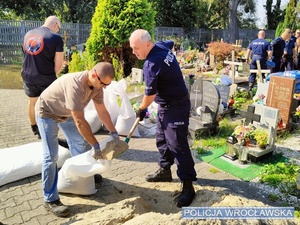 policjanci ładują worki piaskiem