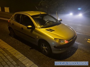 Stojący na jednej z podwrocławskich dróg osobowy peugeot obok oznakowanego radiowozu.