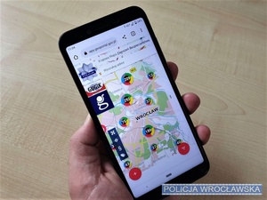Trzymany w dłoni telefon z wyświetloną platformą Krajowej Mapy Zagrożeń Bezpieczeństwa.