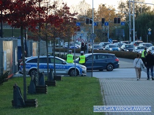 Umundurowani policjanci ruchu drogowego nadzorujący ruch przy jednej z bram wrocławskiego stadionu miejskiego.