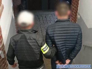 Policjant w ubraniu cywilnym oraz zatrzymany mężczyzna zdjęcie wykonane od tyłu