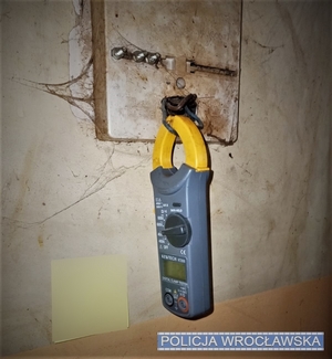 Zdjęcie ilustracyjne miernika prądu wpiętego w zmostkowaną instalację elektryczną w miejscu licznika.