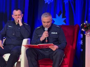 Dwaj policjanci siedzący na fotelach i czytający bajki.