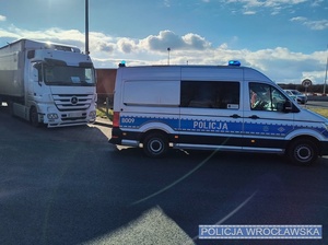 Stojący na jednym z parkingów przy autostradzie A4 pod Wrocławiem oznakowany radiowóz typu bus, a za nim pojazdy ciężarowe.