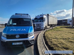 Stojący na jednym z parkingów przy autostradzie A4 pod Wrocławiem oznakowany radiowóz typu bus, a za nim pojazdy ciężarowe.