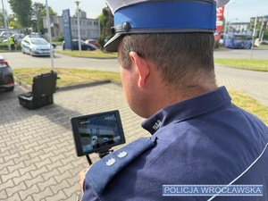 na zdjęciu policjant,który trzyma video rejestrator dronu