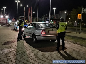na zdjeciu widać pojazd i dwóch policjantów kontrolujących ten pojazd