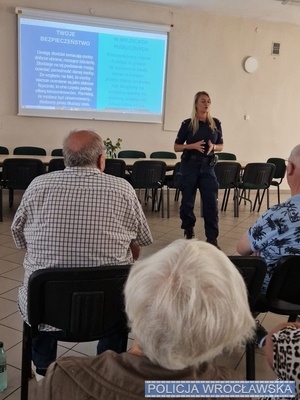 na zdjęciu widać policjantke i tyłem siedzących seniorów