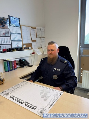 ZDJĘCIE POLICJANTA SIEDZĄCEGO ZA BIURKIEM