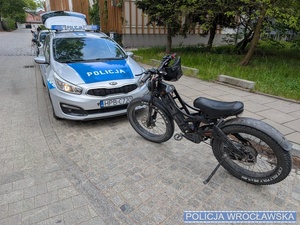 zdjęcie roweru oraz radiowozu policyjnego na drodze
