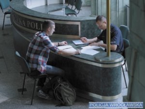 Kandydat siedzi przy biurku podczas składania dokumentów aplikacyjnych, po drugiej stronie siedzi policjant Wydziału Kadr