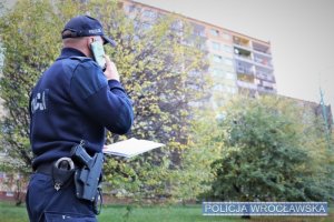 Policjant rozmawiający przez telefon - sprawdzanie osób na kwarantannie