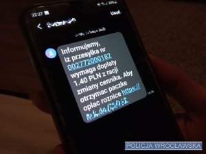 Ekran telefonu, na którym widnieje treść SMS o konieczności opłacenia różnicy w kwocie 1.40 pln do przesyłki.