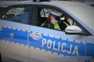 Policjantka wrocławskiego Wydziału Ruchu Drogowego w radiowozie: widok przez uchyloną szybę