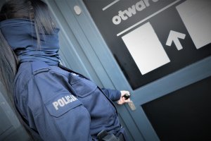 Zdjęcie przedstawia policjantkę stojącą przy drzwiach